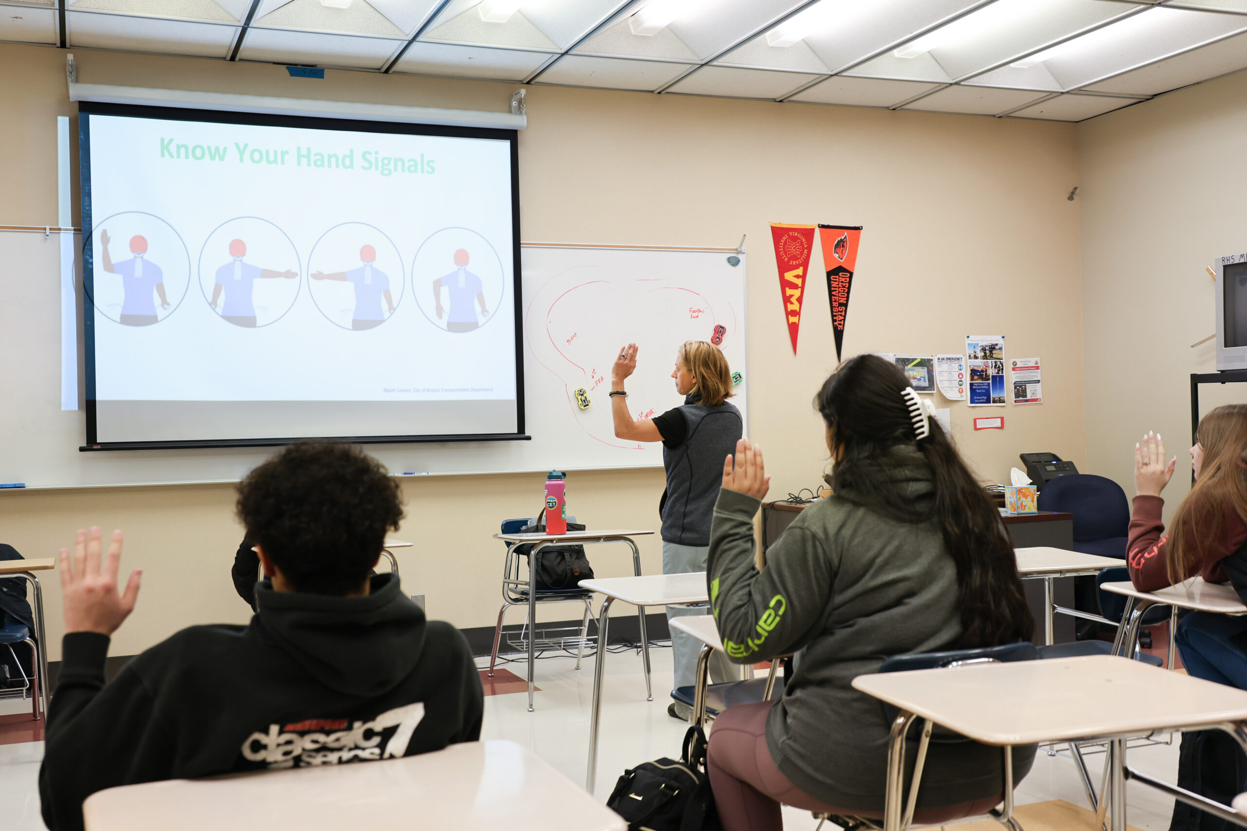 An instructor and students practice traffic hand signals in an Oregon driver safety training classroom.